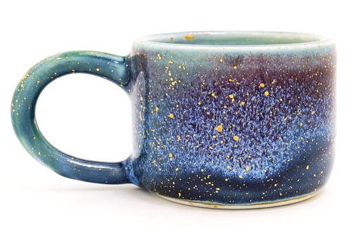 Blue ceramic mug with speckled pattern on a white background