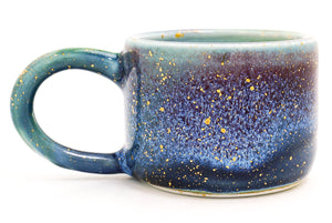 Blue ceramic mug with speckled pattern on a white background